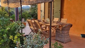 An outdoor patio with wicker furniture, a table set for dining, and a potted plant.