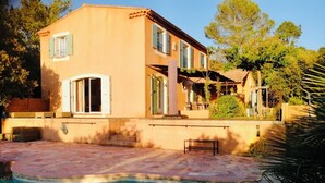 A two-story house with a swimming pool, outdoor furniture, and a pergola.