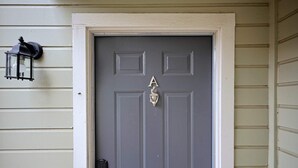 A gray front door with a silver letter 'A' and a door knocker.