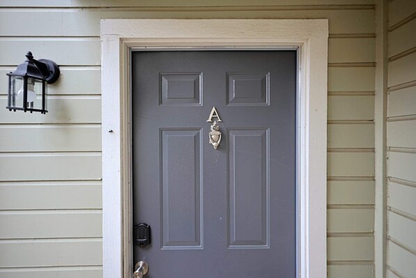 A gray front door with a silver letter 'A' and a door knocker.