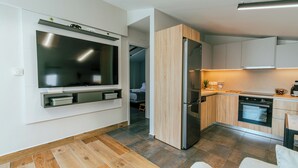 Una cocina moderna con horno empotrado, refrigerador y televisor de pantalla plana montado en la pared.