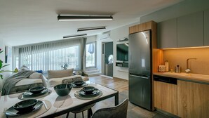 Una cocina moderna con refrigerador integrado, armarios de madera y un comedor con mesa dispuesta para cuatro.
