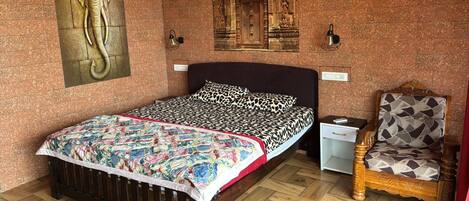 A bedroom with a bed, a chair, a nightstand, and a wall-mounted lamp.