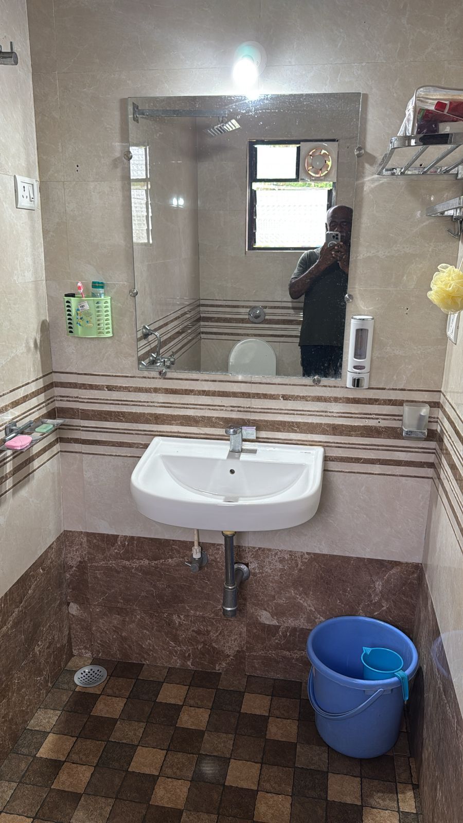 A bathroom with a sink, mirror, and a blue bucket.