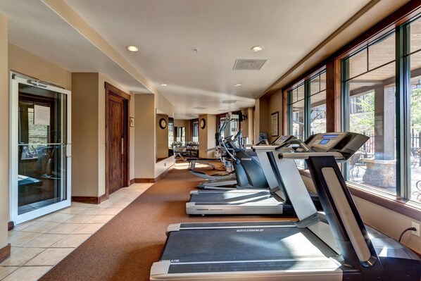 Un gimnasio con cintas de correr, bicicletas estáticas y un espejo grande.