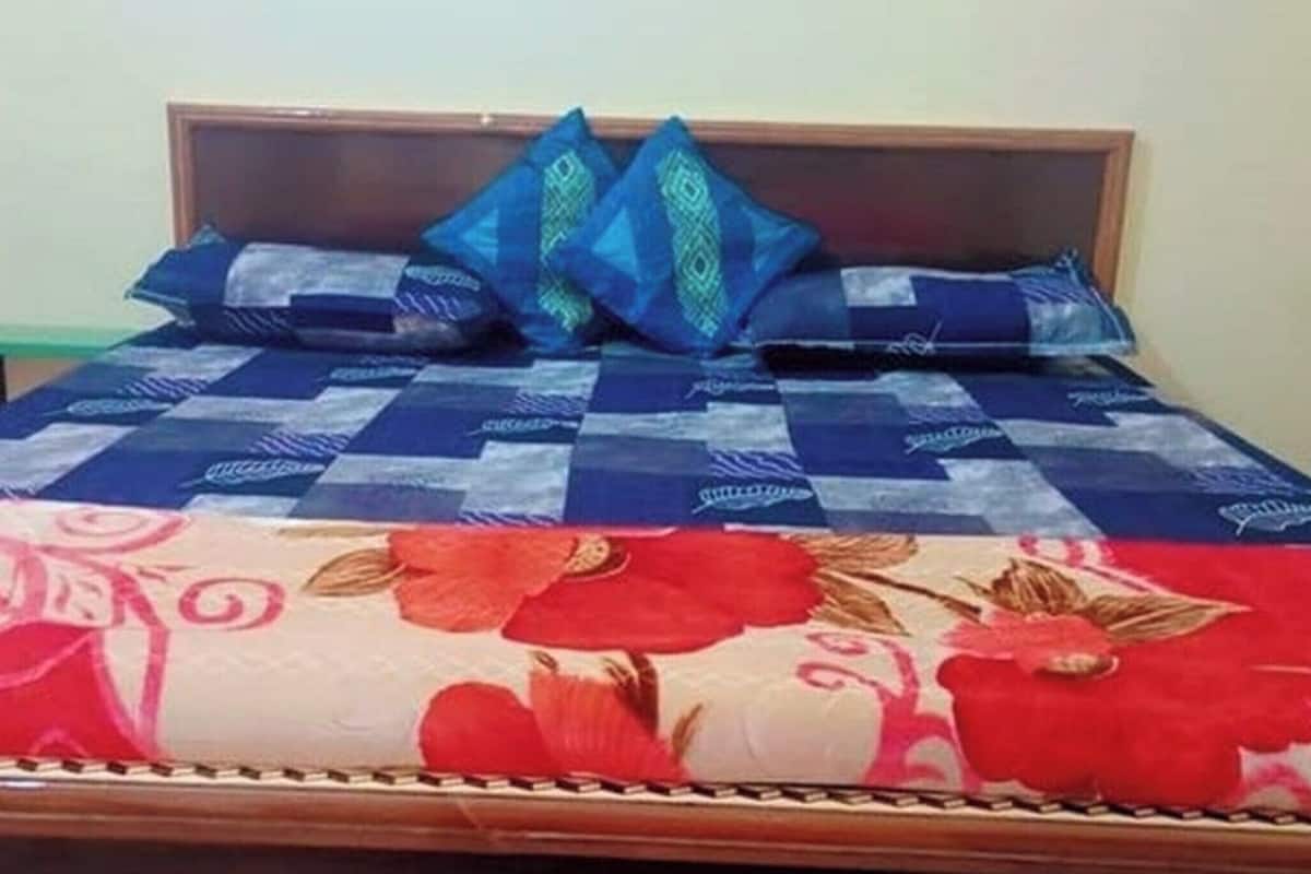 A bed with a checkered bedspread and two decorative pillows.