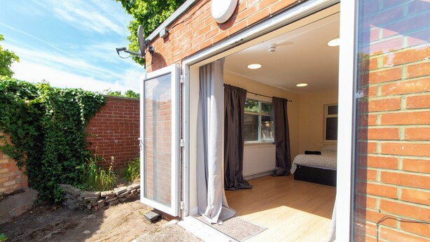 Una habitación con una cama, una ventana y una puerta que da al exterior.