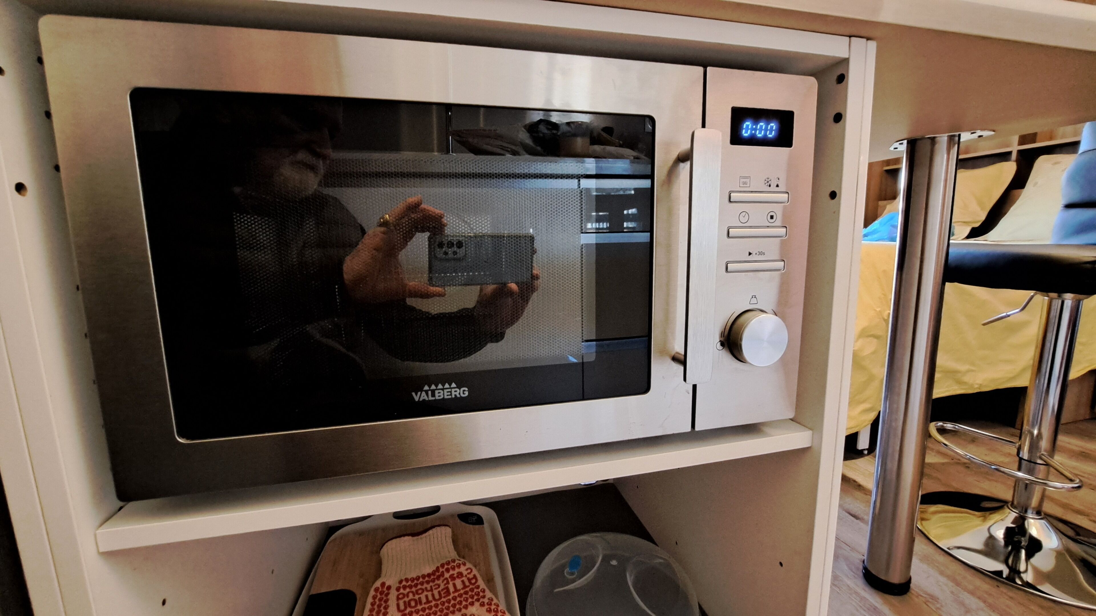 A stainless steel microwave oven with a digital display, a control panel with buttons, and a timer.