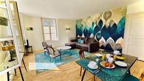 A modern living room with a dining area, a sofa, and a colorful abstract wall art. - La Chocolaterie, Dream stay, Majestic view of the Chapelle Saint-Hubert (Unknown)