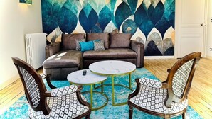 A living room with a brown sofa, two patterned chairs, a round coffee table, and a large abstract painting on the wall. - La Chocolaterie, Dream stay, Majestic view of the Chapelle Saint-Hubert (Unknown)