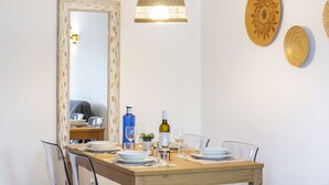 A dining area with a wooden table set for four, a large mirror, a hanging light fixture, and decorative plates on the wall. - 46 Terraços de Bengil (Casa do Riso) (Benagil)