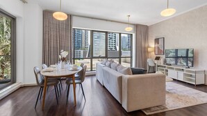 A modern living room with a dining area, large windows, and a flat-screen TV.
