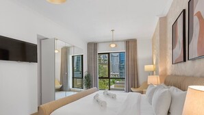 A modern hotel room with a large bed, a TV mounted on the wall, and a view of the city through the window.