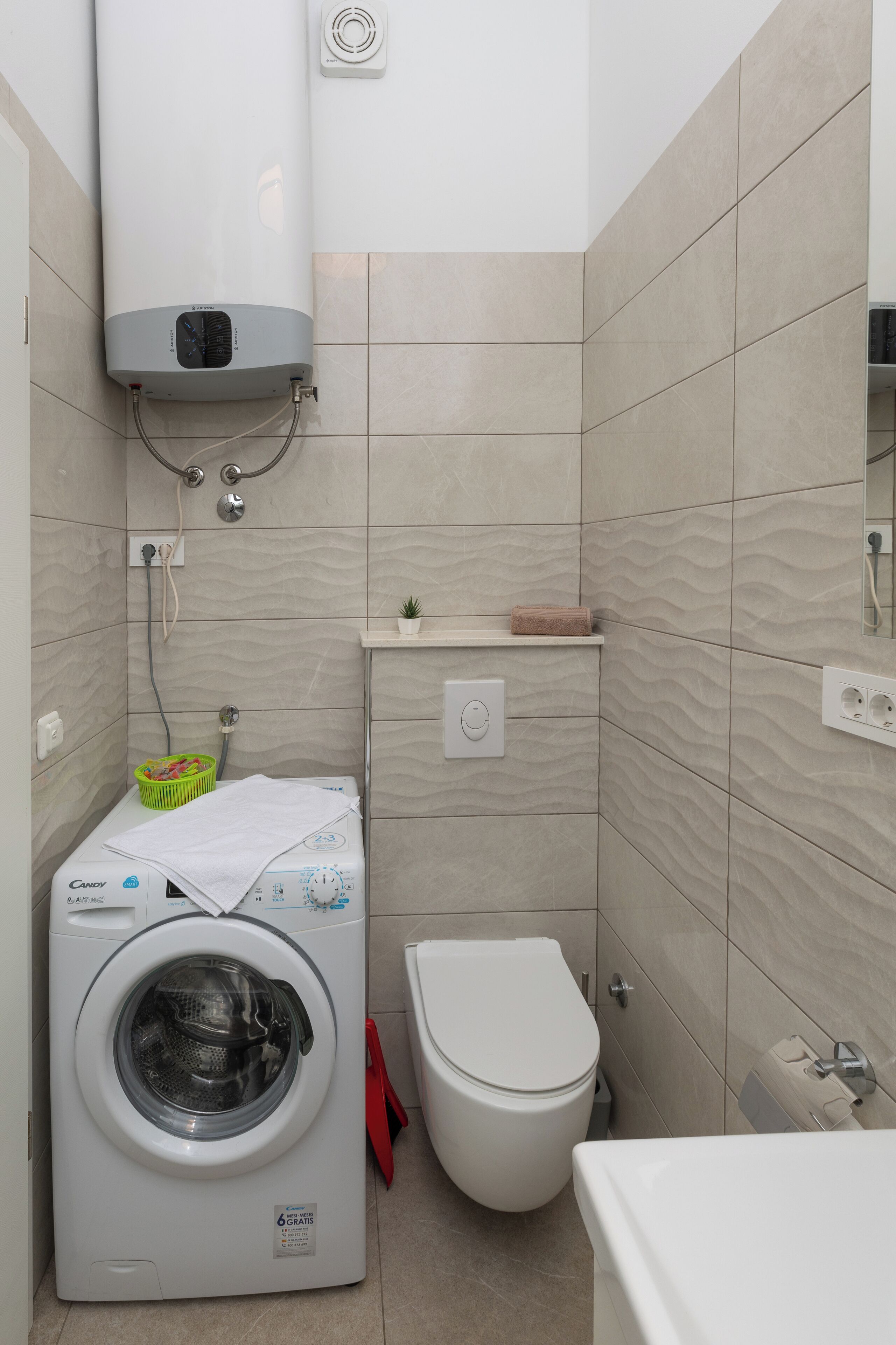 Ein kleines Badezimmer mit Waschmaschine, Toilette und Handtuchhalter.