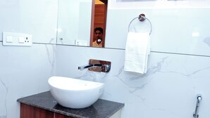 A modern bathroom with a white sink, wooden vanity, marble walls, a towel rack, and a shower. - GREEN HILLS HOTEL (Pithoragarh)