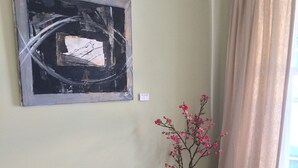 Une pièce avec un bureau en bois foncé, un vase blanc contenant des fleurs roses et un tableau abstrait encadré accroché au mur.