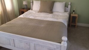 Un lit bien fait, avec une tête de lit blanche et un plaid beige.