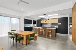 Une cuisine moderne dotée d’un îlot central, de meubles de couleur noire et d’un coin repas avec des chaises vertes.