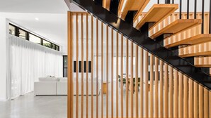 A modern interior with a staircase, wooden slats, and a white sofa. - Villa Hitam - Burleigh Heads (Gold Coast)