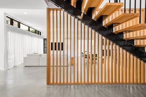 A modern interior with a staircase, wooden slats, and a white sofa.