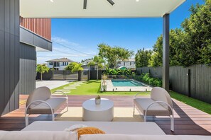 Une terrasse extérieure avec deux chaises blanches, une table ronde et une petite piscine.