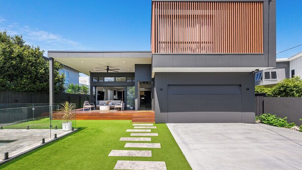 A modern two-story house with a covered patio, a garage, and a well-maintained lawn with stepping stones. - Villa Hitam - Burleigh Heads (Gold Coast)