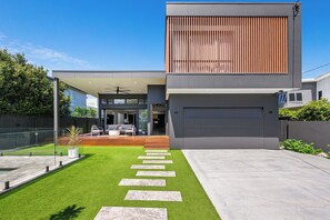 A modern two-story house with a covered patio, a garage, and a well-maintained lawn with stepping stones. - Villa Hitam - Burleigh Heads (Gold Coast)