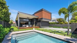 A modern house with a swimming pool, a covered outdoor seating area, and a well-maintained garden. - Villa Hitam - Burleigh Heads (Gold Coast)
