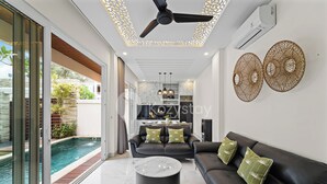 A modern living room with a black leather sofa, a marble coffee table, and a ceiling fan.
