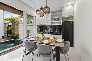 Una cocina moderna con isla integrada, encimeras de mármol y zona de comedor con vista a la piscina.