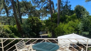 A patio with white chairs and a green table, surrounded by trees and a white umbrella. - House in Cap Ferret, Canon village, just a few minutes walk from the beach! (Lège-Cap-Ferret)