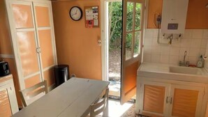 A kitchen with a white table, a clock, and a window. - House in Cap Ferret, Canon village, just a few minutes walk from the beach! (Lège-Cap-Ferret)