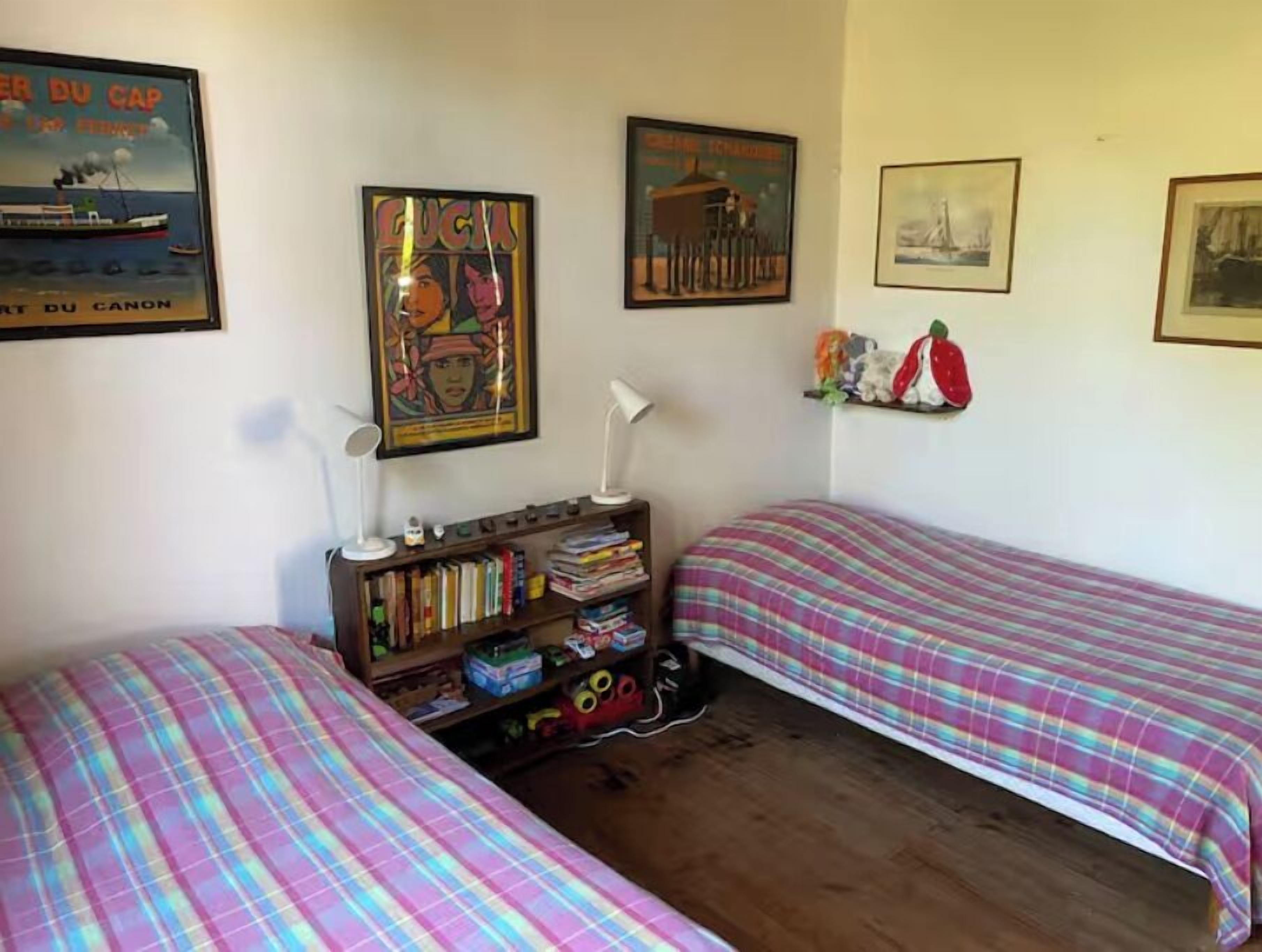 A bedroom with two beds, a bookshelf, and various wall decorations including posters and a shelf with figurines.