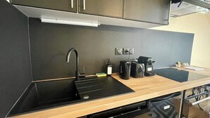 A modern kitchen with a black countertop, stainless steel cabinets, and a dishwasher. - La Colombage, Charming stay on the Place du Château (Amboise)