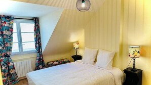 A bedroom with a bed, two bedside tables with lamps, a radiator, and a window with curtains. - La Colombage, Charming stay on the Place du Château (Amboise)