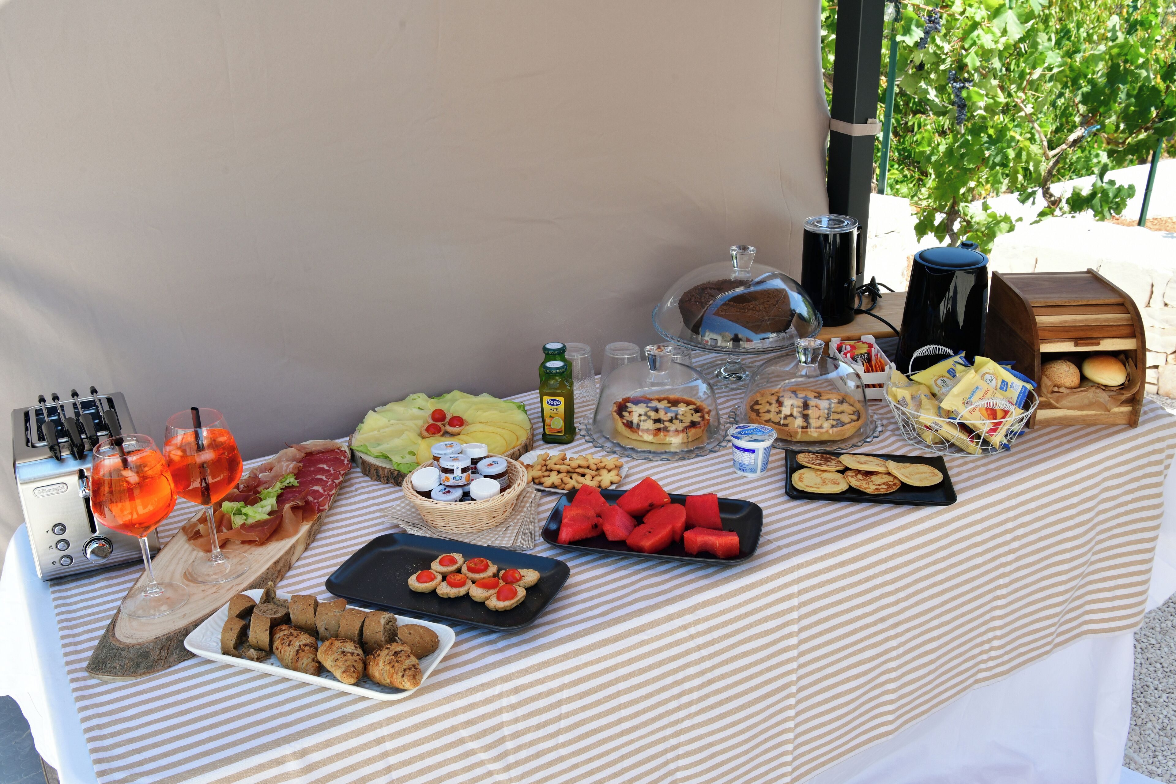 Una mesa de buffet con diversos alimentos, como frutas, pasteles y una estación de café.