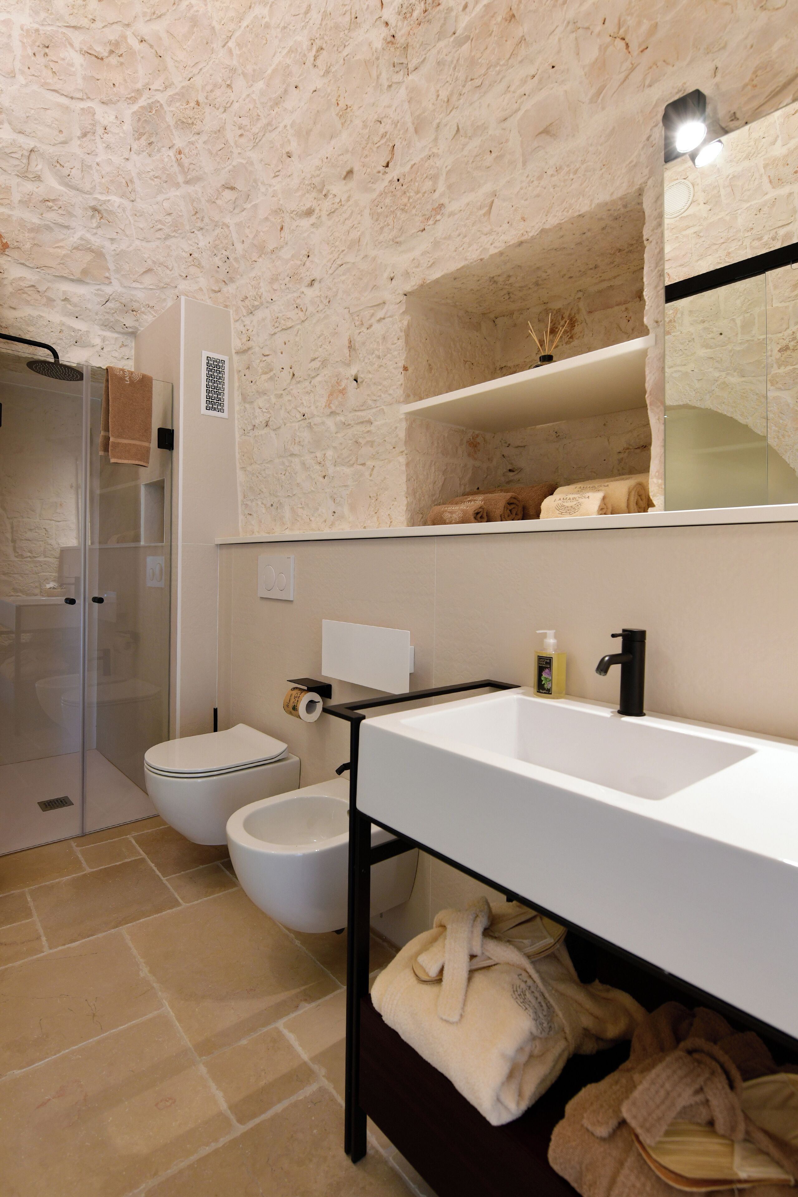 A bathroom with a stone ceiling, a white sink, a toilet, and a glass-enclosed shower.