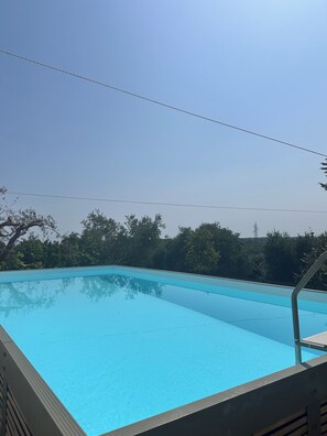 A clear blue swimming pool with a metal ladder and a metal railing.