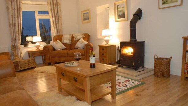 Un salón acogedor con sofá, una mesa de centro de madera, chimenea y ventana con cortinas.