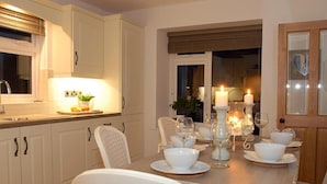 Comedor con una mesa preparada para cuatro personas, sillas blancas y velas.