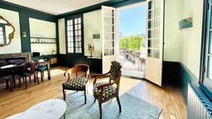 A room with a dining area, two chairs, a table, and a large window with a view of the street. - La Chapelle, exceptional view of the castle square with balcony (Amboise)