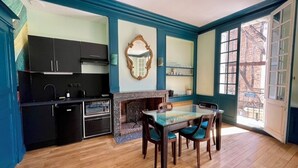 A kitchen with a dining table and chairs, a fireplace, and a large window. - La Chapelle, exceptional view of the castle square with balcony (Amboise)