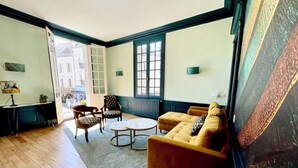 A room with a sofa, two armchairs, a small table, and a view of a building through a window. - La Chapelle, exceptional view of the castle square with balcony (Amboise)