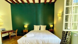 A bedroom with a large bed, two bedside lamps, a desk with a chair, and a window with curtains. - La Chapelle, exceptional view of the castle square with balcony (Amboise)