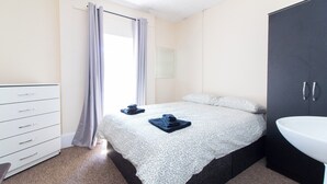 A bedroom with a bed, a dresser, a mirror, and a sink. - Brookvale Guest House Room 10 (Southampton)
