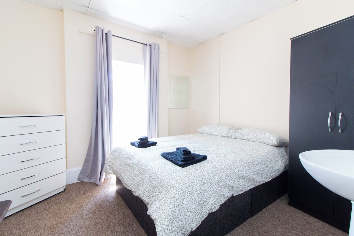 Ein Schlafzimmer mit einem Bett, einem Schminktisch, einem Spiegel und einem Waschbecken.