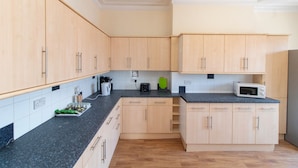 A kitchen with light wooden cabinets, a black granite countertop, a microwave, and a toaster. - Brookvale Guest House Room 10 (Southampton)