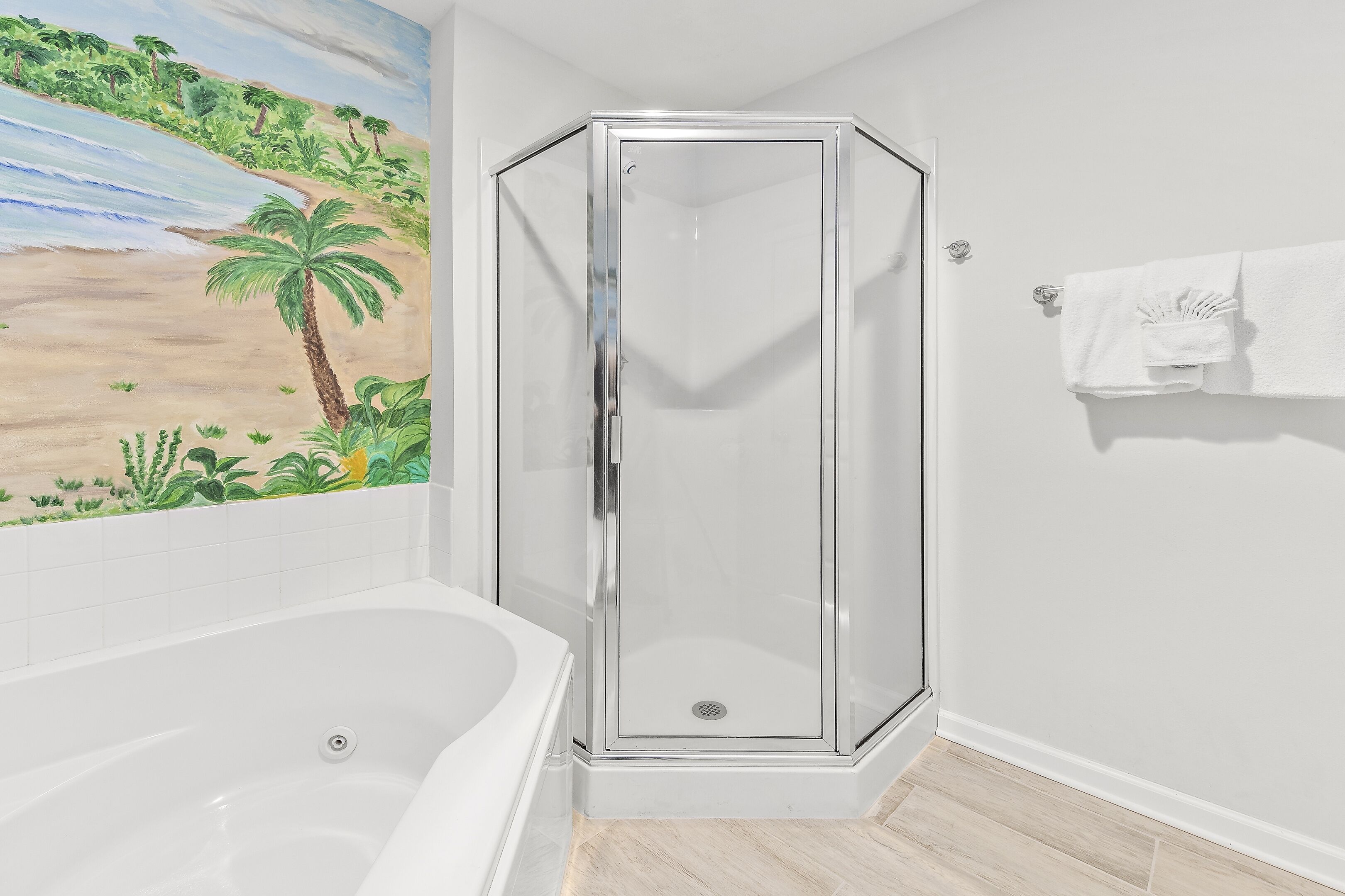 Une salle de bain avec une douche à parois de verre, une baignoire et une fresque murale représentant une scène de plage.
