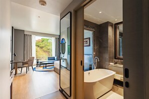 A modern bathroom with a large bathtub, a mirror, and a shower area. - Radisson Hotel Jamshedpur (Jamshedpur)