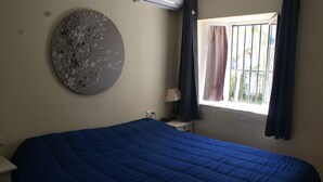 A room with a large bed, a round wall decoration, a window with curtains, and a bedside table with a lamp. - Andalusian vacations (San Juan de los Terreros)